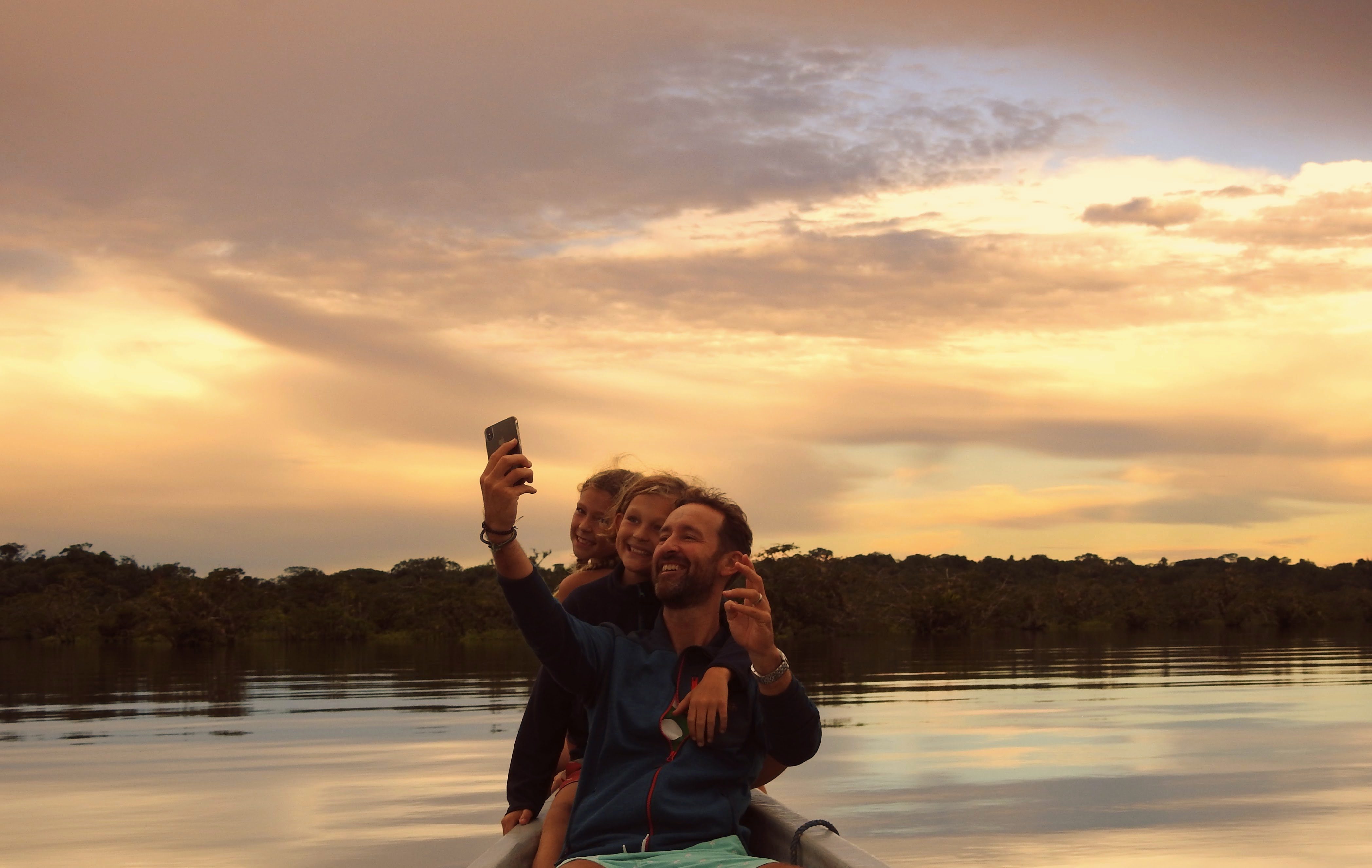 a family with children taking a selfie in the amazon river at dusk