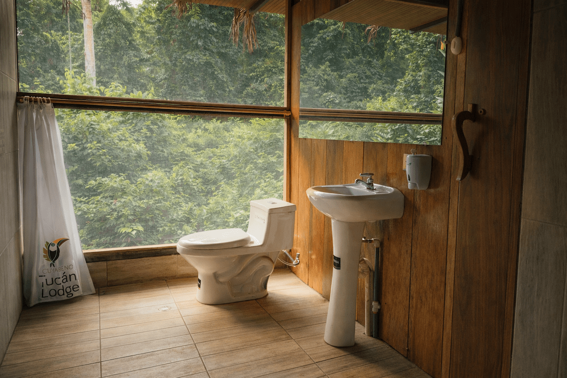 Clean private bathroom with rainforest views inside an Amazon eco-lodge cabin.