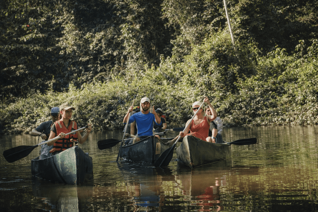 amazon-river-canoe-wildlife-excursion Small group paddling canoes through a calm Amazon river surrounded by rainforest