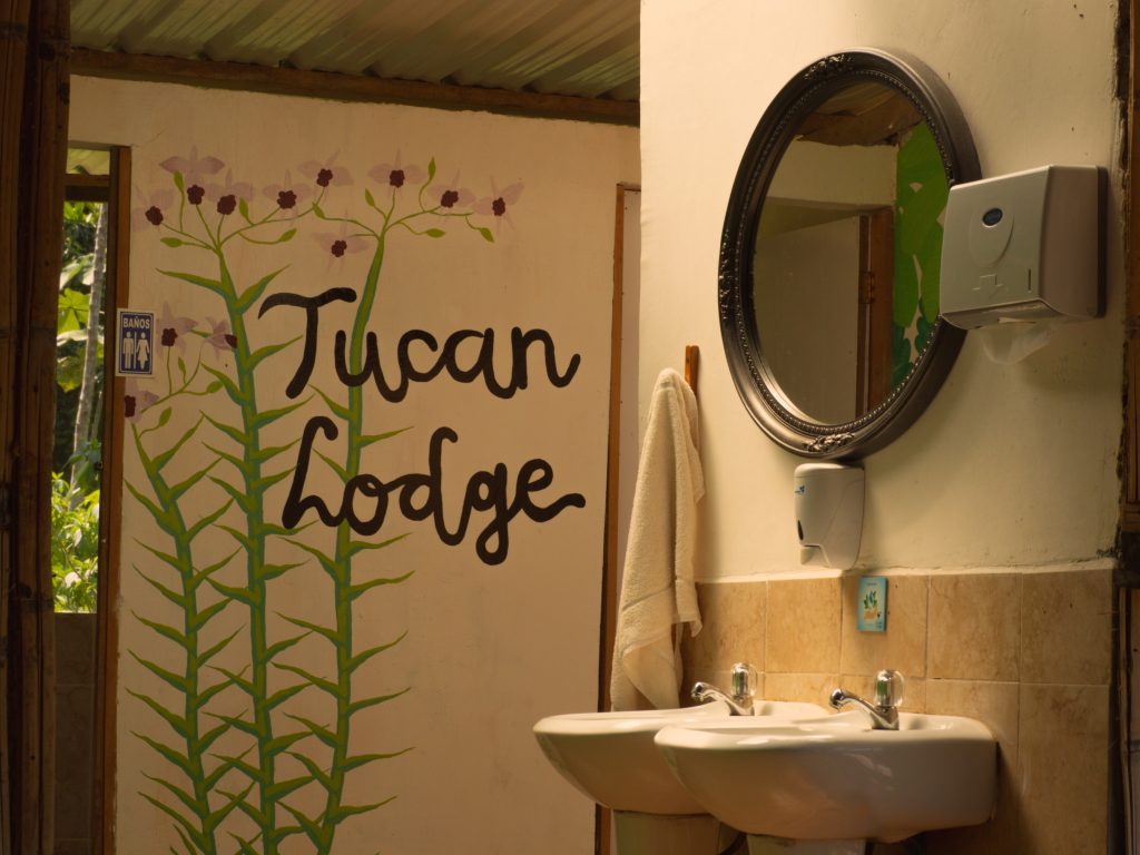 Interior del baño compartido en Tucán Lodge, con arte mural de la selva y comodidades de eco-lodge en la Amazonía