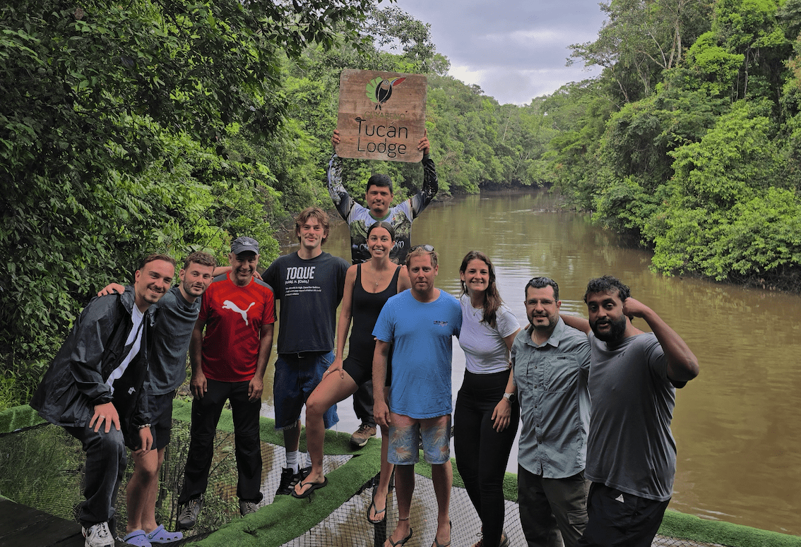 Small group of guests celebrating their arrival at Cuyabeno Tucán Lodge along a rainforest river in the Amazon.
