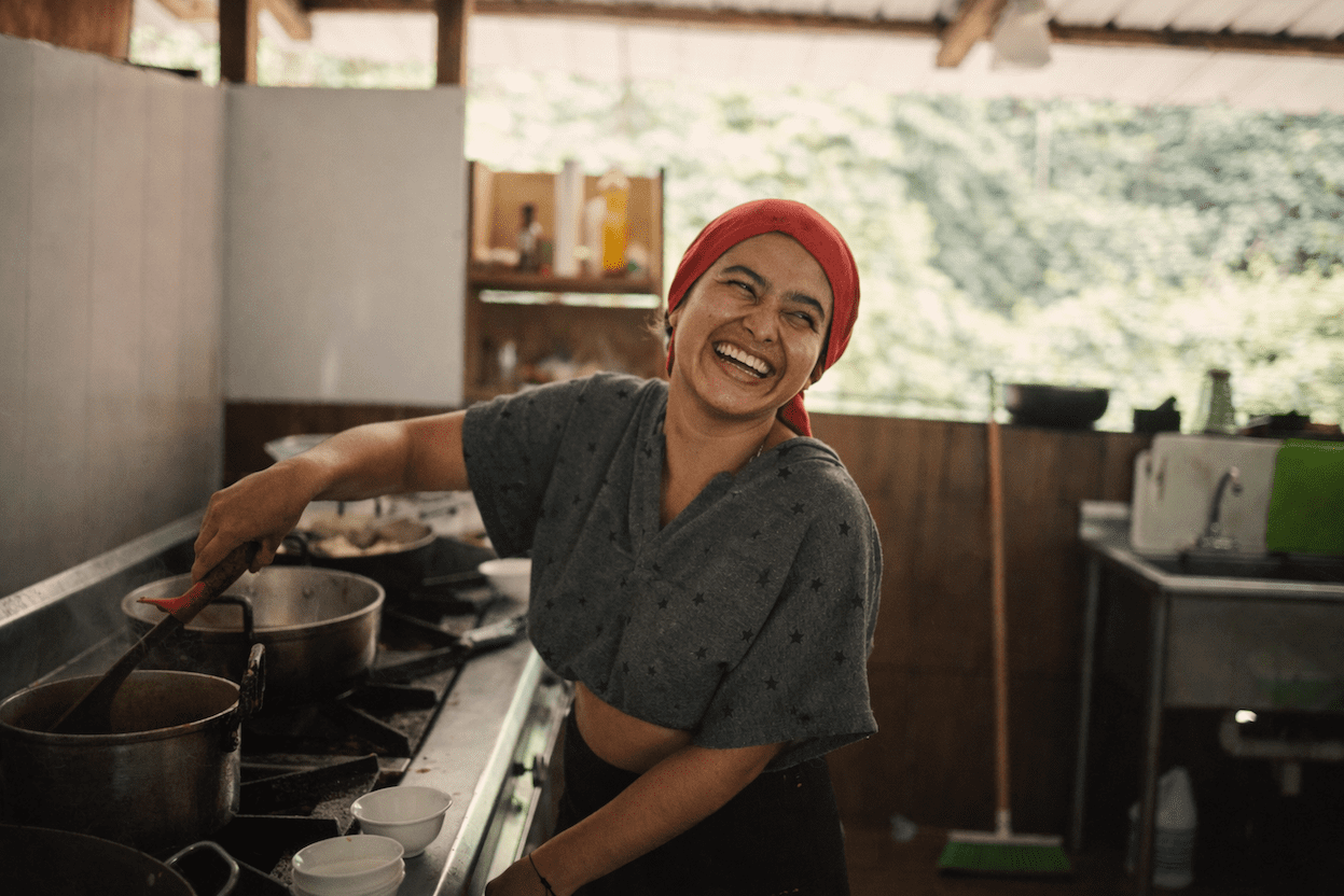 Smiling local cook preparing a meal in the open kitchen of a rainforest eco-lodge