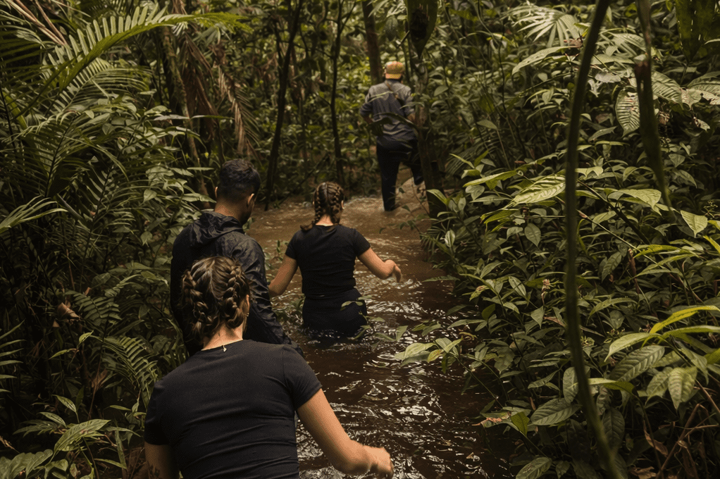 Visitantes avanzando por un sendero inundado durante una caminata guiada en la selva amazónica