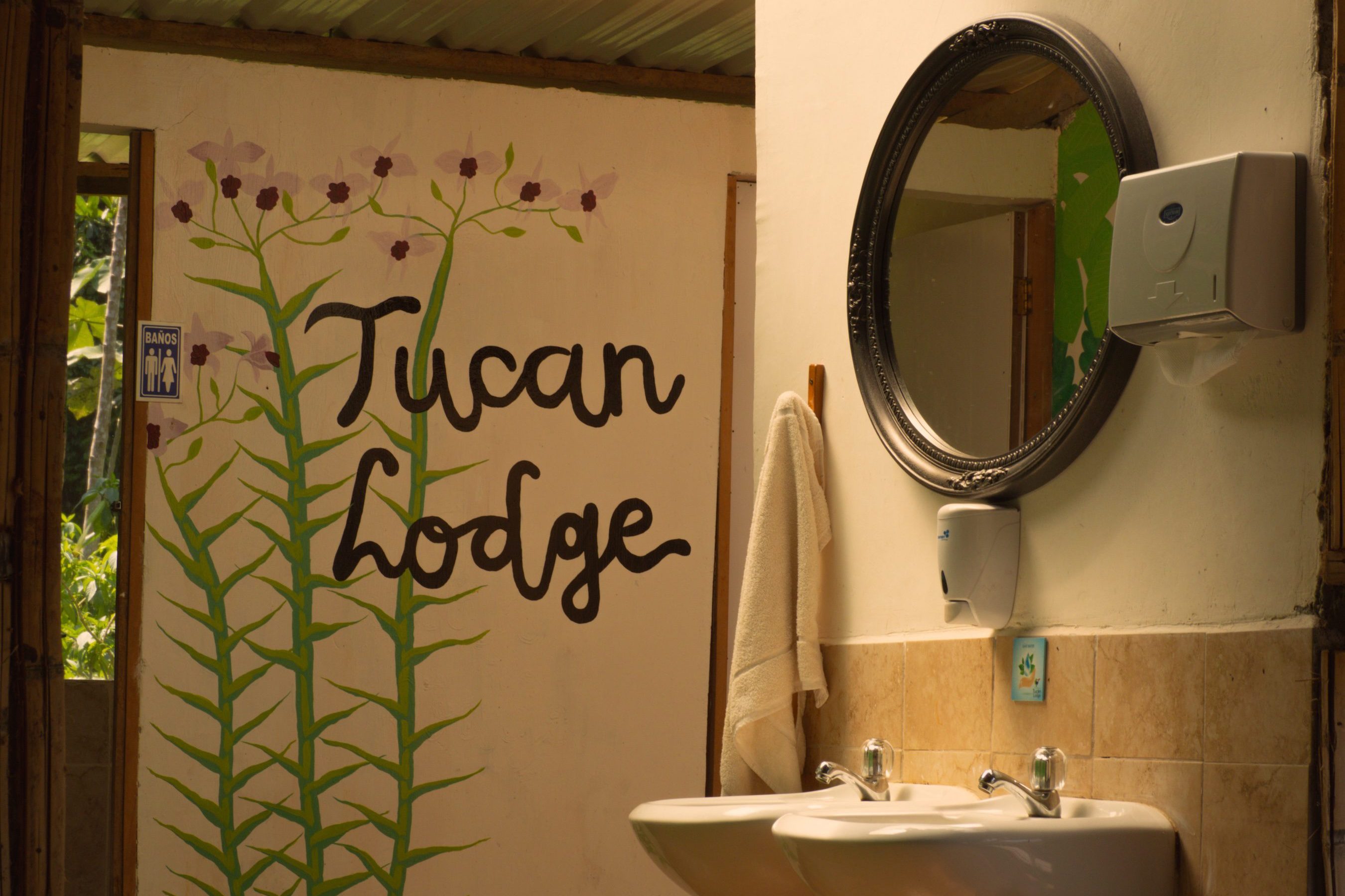Interior of the shared bathroom at Tucan Lodge, featuring hand-painted rainforest artwork and eco-lodge amenities in the Amazon